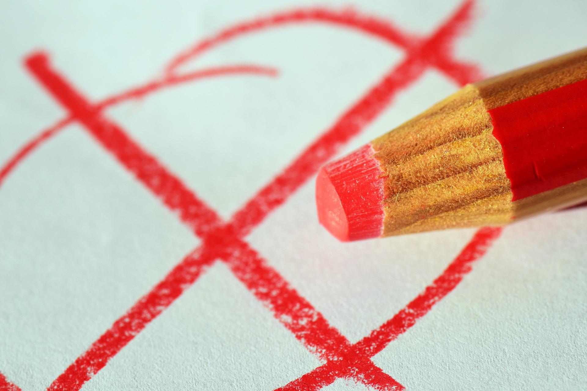 Mit einem roten Stift auf ein Papier gezeichnetes Kreuz wie beim Wählen