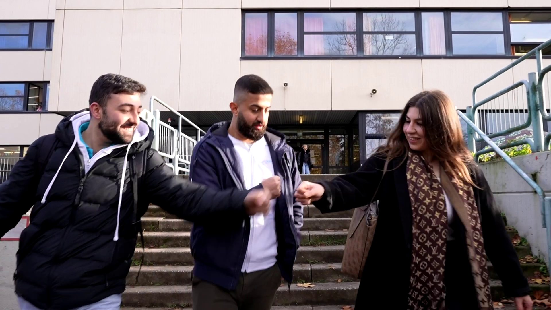 Sami, Alan und Fatema geben sich nach ihrem Einsatz triumphierend einen Faustgruß vor der Schule