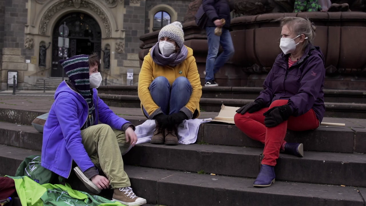 Man sieht drei Personen verschiedenen Alters, die alle in der Klimaschutzbewegung aktiv sind