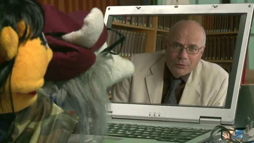 Zwei Handpuppen schauen auf TV-Bildschirm mit Gusy.