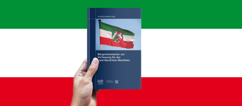 Eine Hand hält das Buch, als Hintergrund sind die NRW-Farben Grün-Weiß-Rot zu sehen.